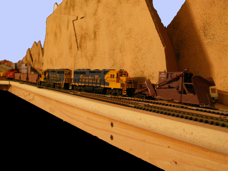 A maintaince of way train heads out to work with a spreader on the point and three balast hoppers behind a pair of GP40 locomotives