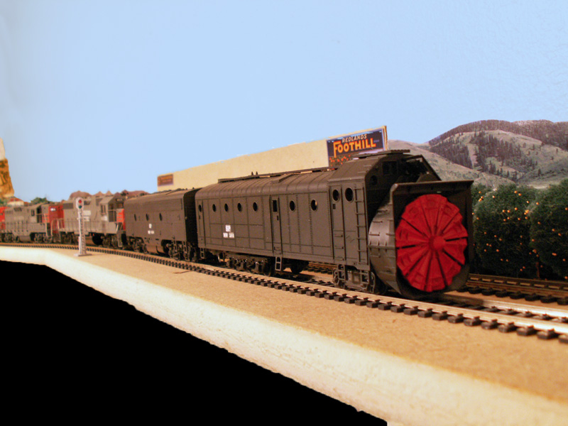 A rotary snow plow heads up the foothills towards Wolf Mountain