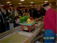 Duane Miner (wearing black sweat shirt in the background) watches trains while Don Confarotta monitors the accessory modules.