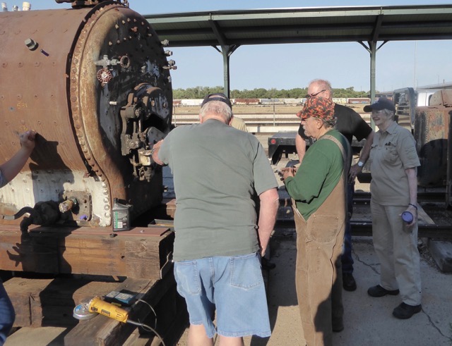 John in green shirt discusses boiler issues with the crew