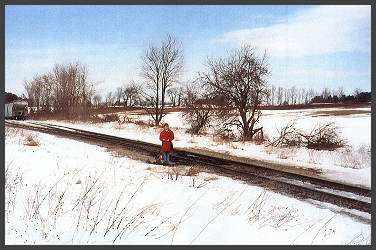 Paul's wife, Susan, stands at the same spot Ruth met the freight train 55 years ago. The farm in the upper right corner is where the men started their search on foot. &copy; 2/29/2004 Paul S. Worboys (25K)